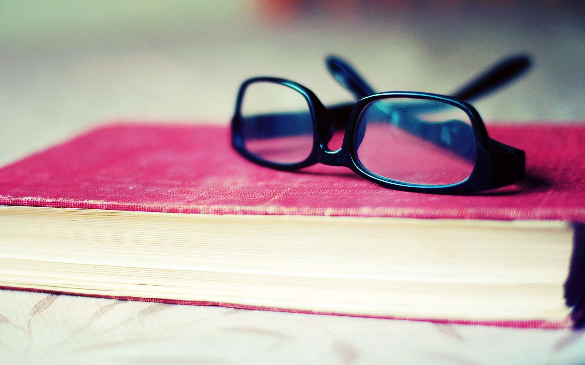 closed book and pair of reading glasses on table