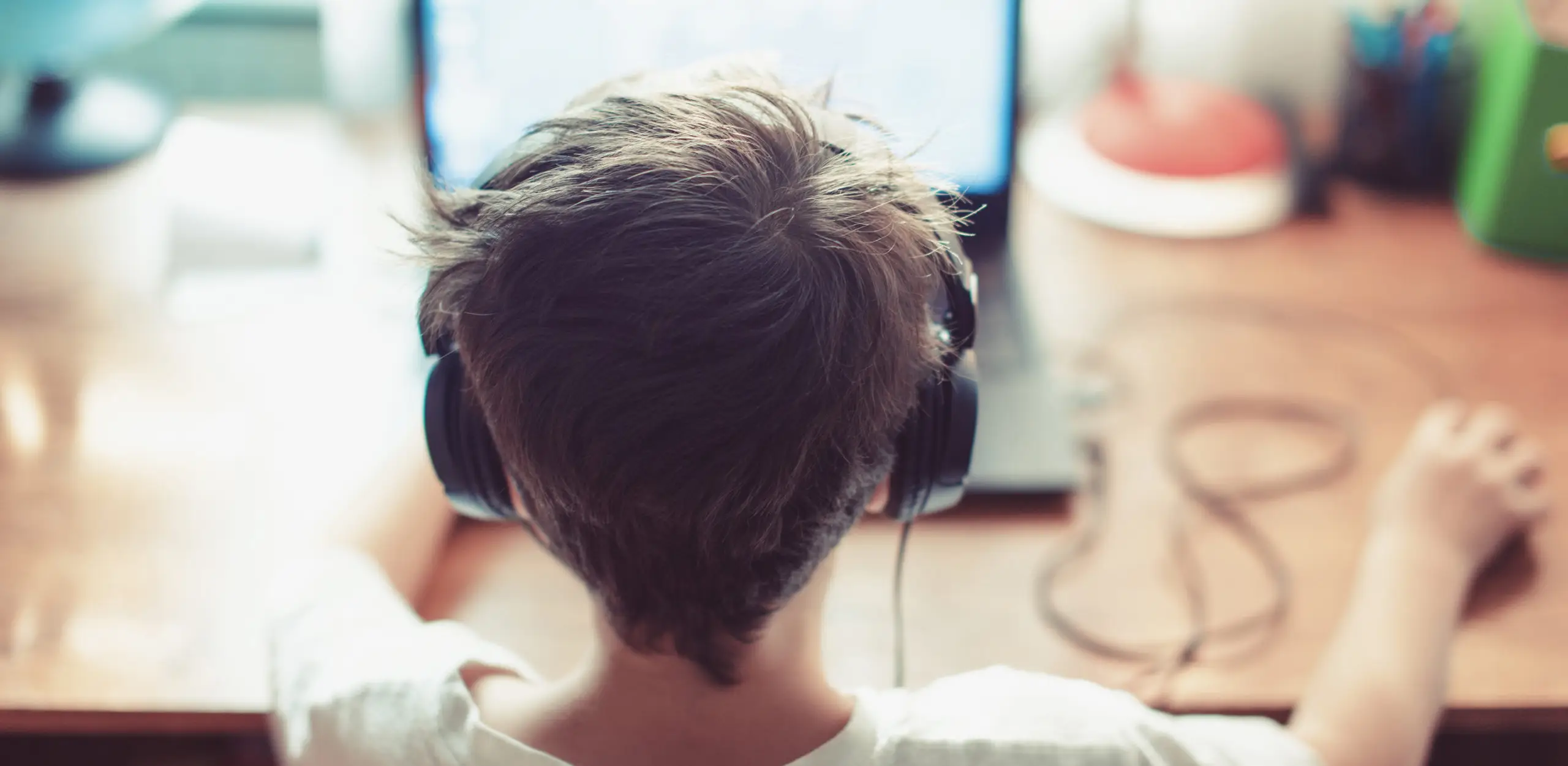 young boy wearing headphones sitting in front of computer