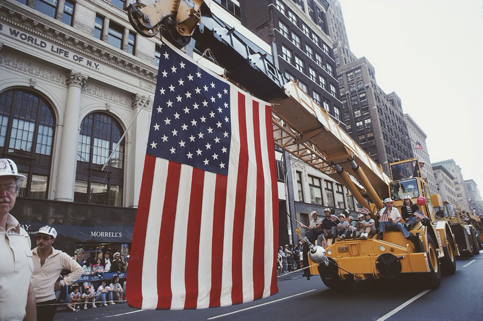 A large American flag is suspended from a crane in a Labor Day parade in New York City, 1982. Barbara Alper — Getty Images