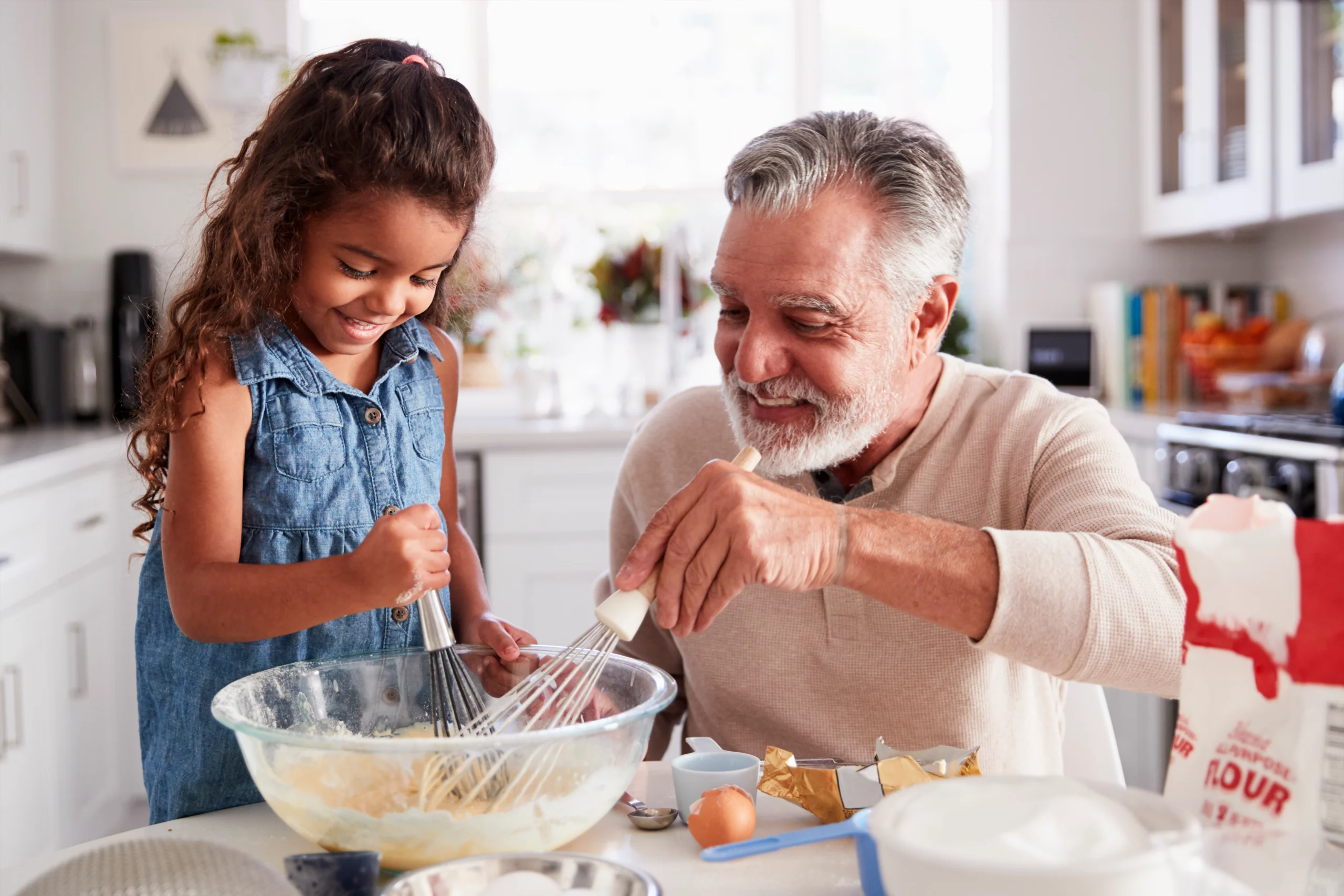 grandfather and granddaughter mixing cake ingredients in kitchen
